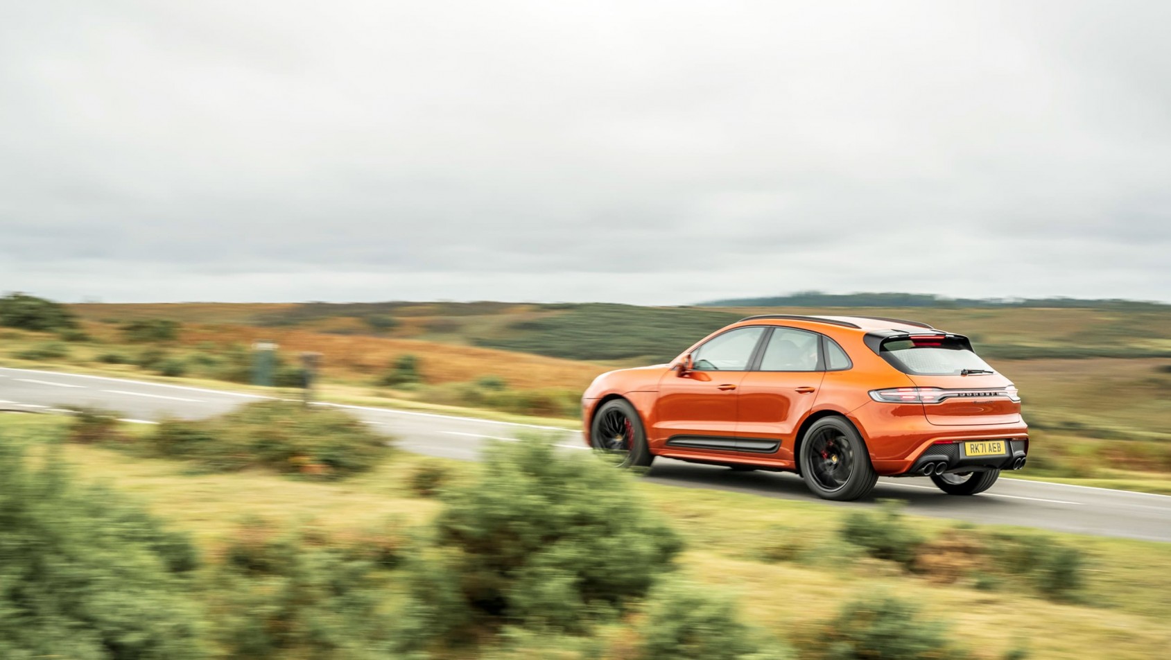 Porsche Macan jedzie z dużą prędkością po drodze - widziany z tyłu