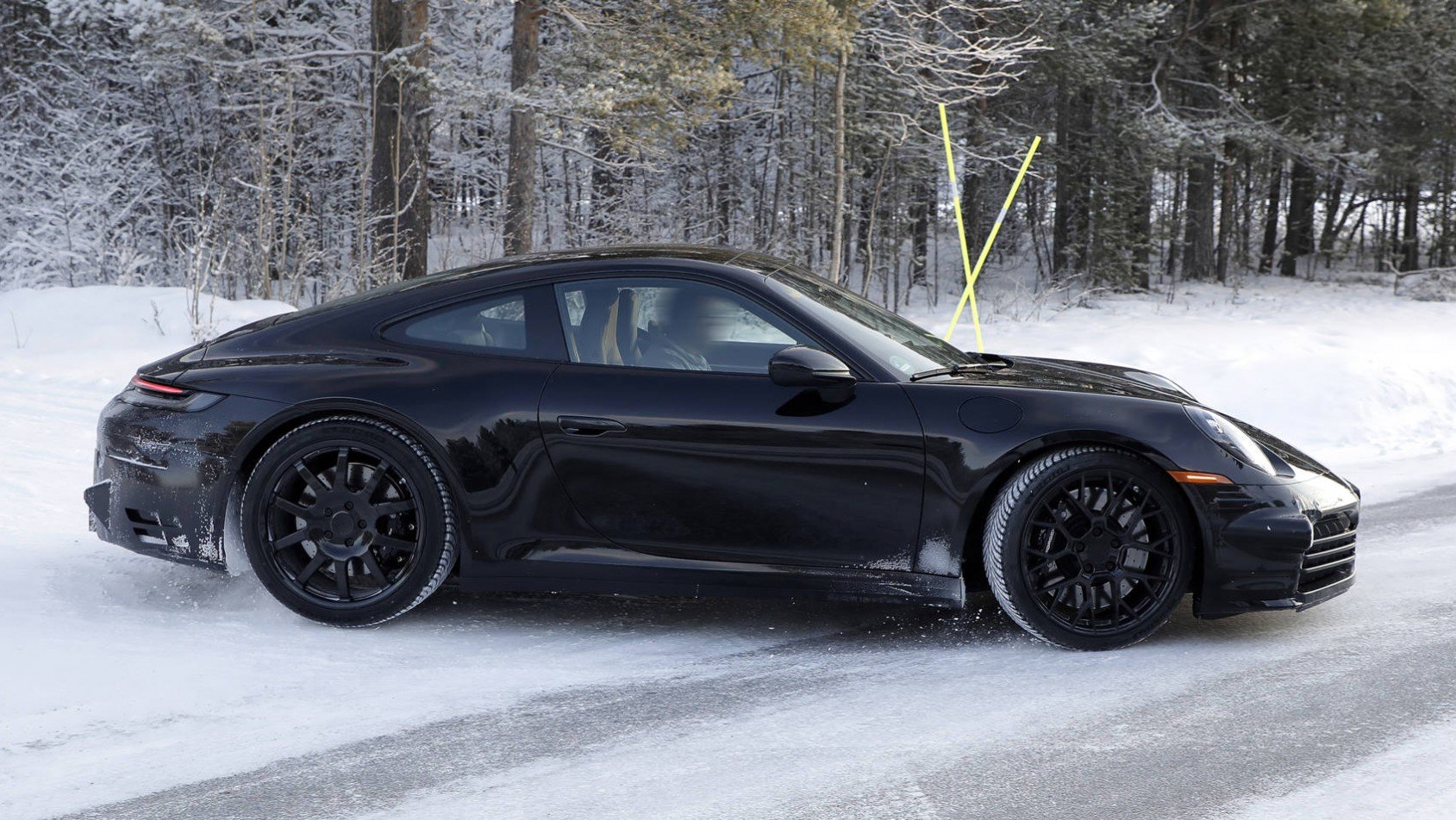 Czarne Porsche 911 generacji 992.2 na śniegu bok