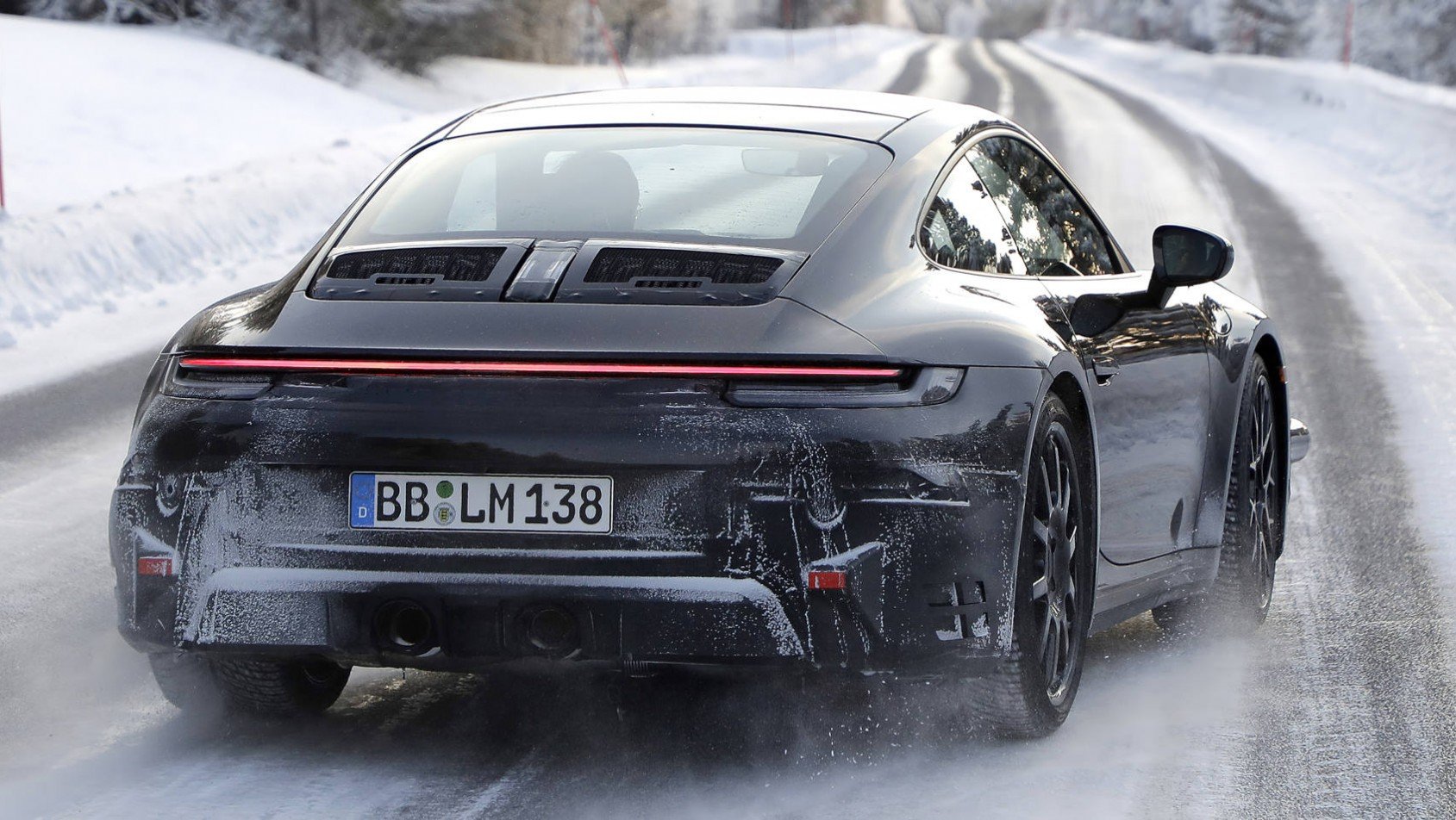 Czarne Porsche 911 generacji 992.2 na śniegu tył