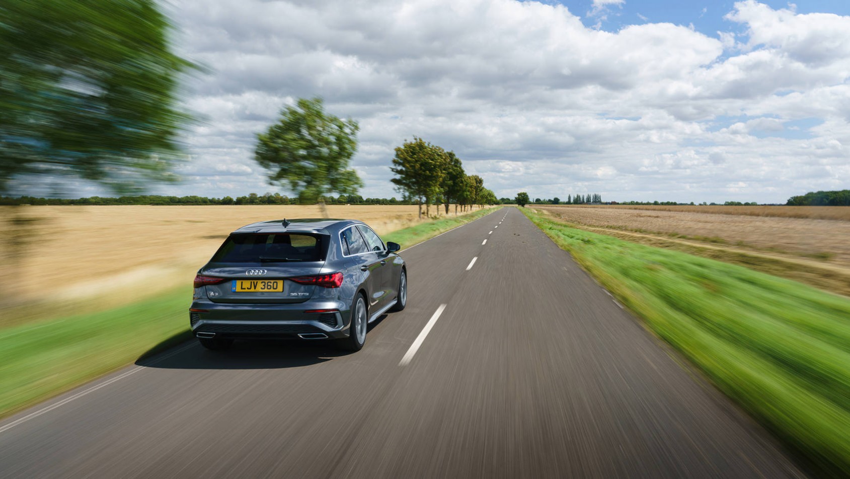 Nowe Audi A3 szybko porusza się po drodze za miastem
