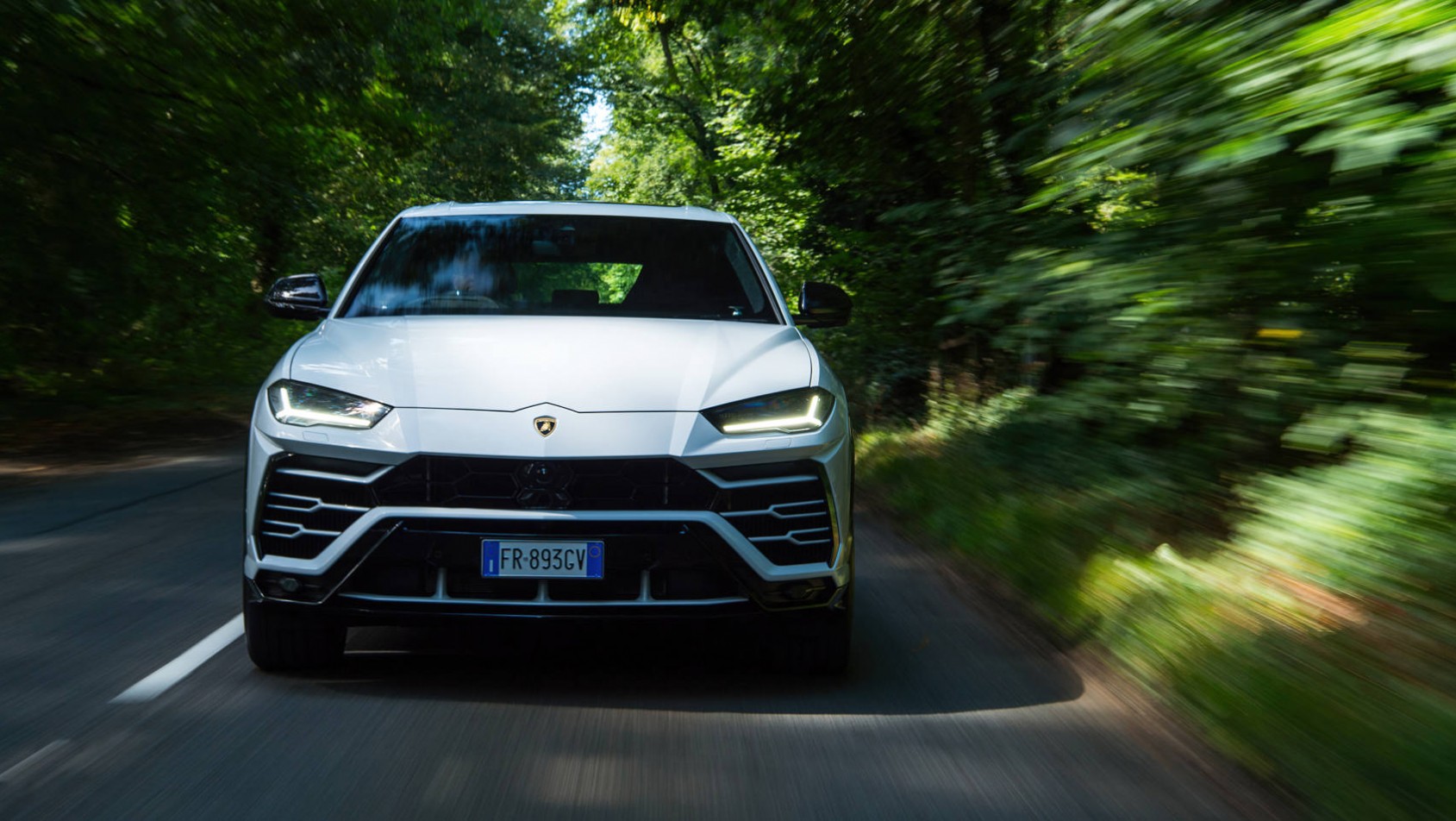 Biały Lamborghini Urus pośród drzew