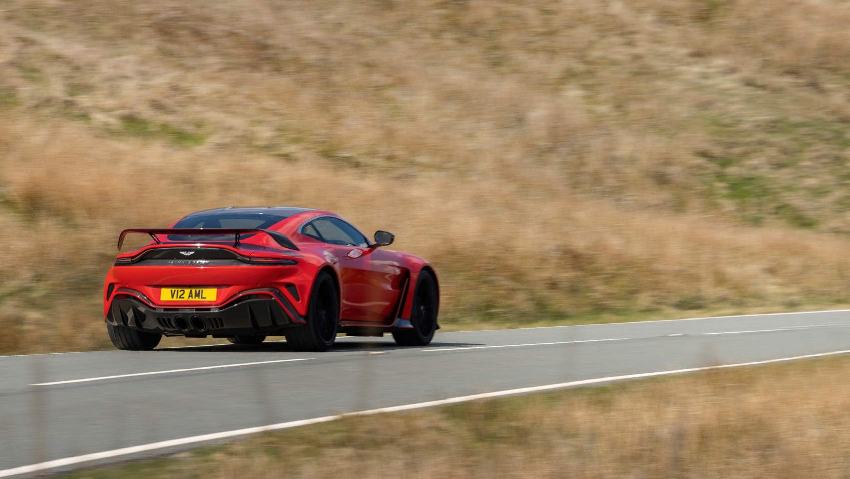 Aston Martin V12 Vantage poruszający się na pustej drodze