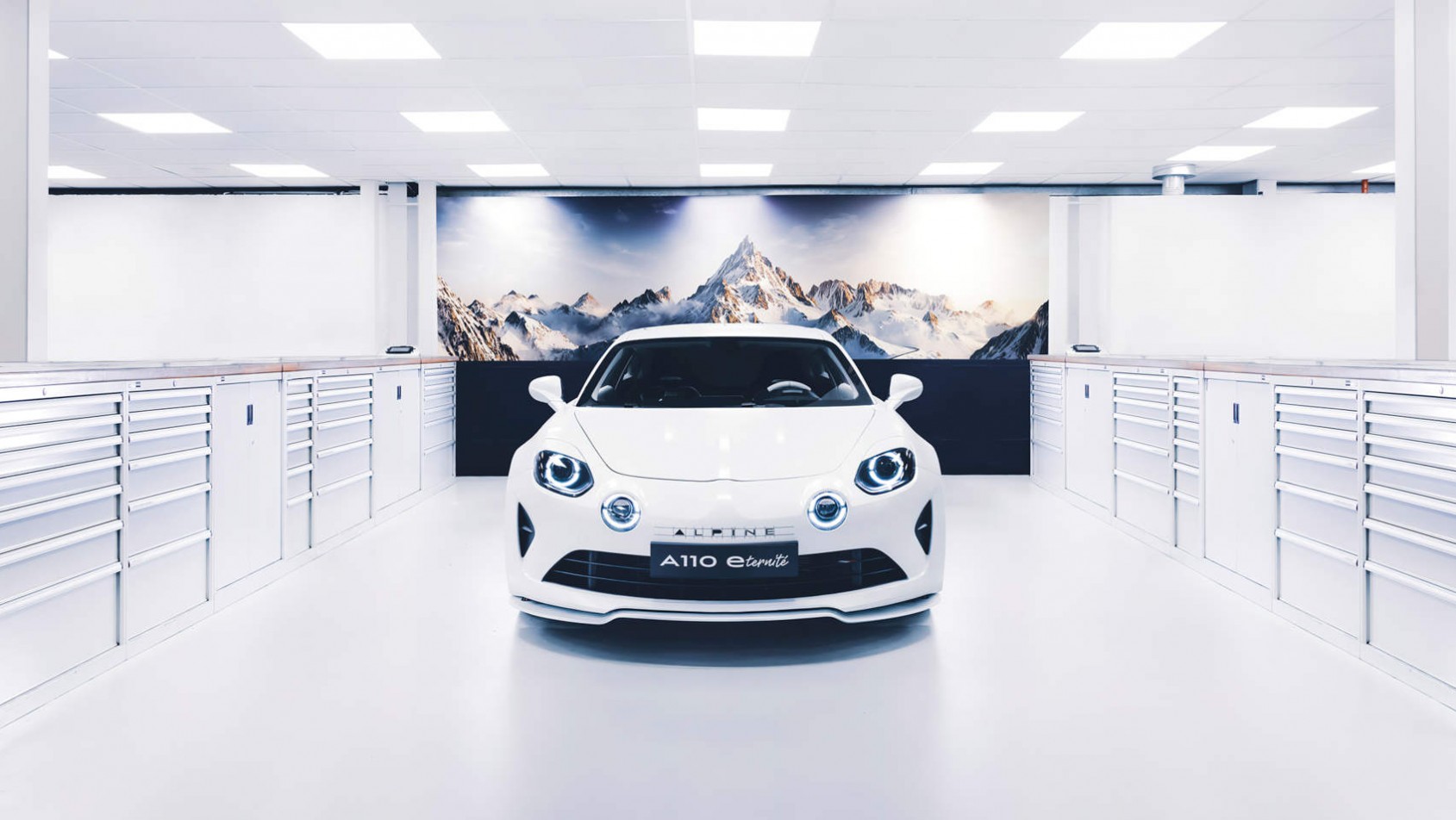 Alpine A110 E-Ternité - w garażu na tle plakatu z górami
