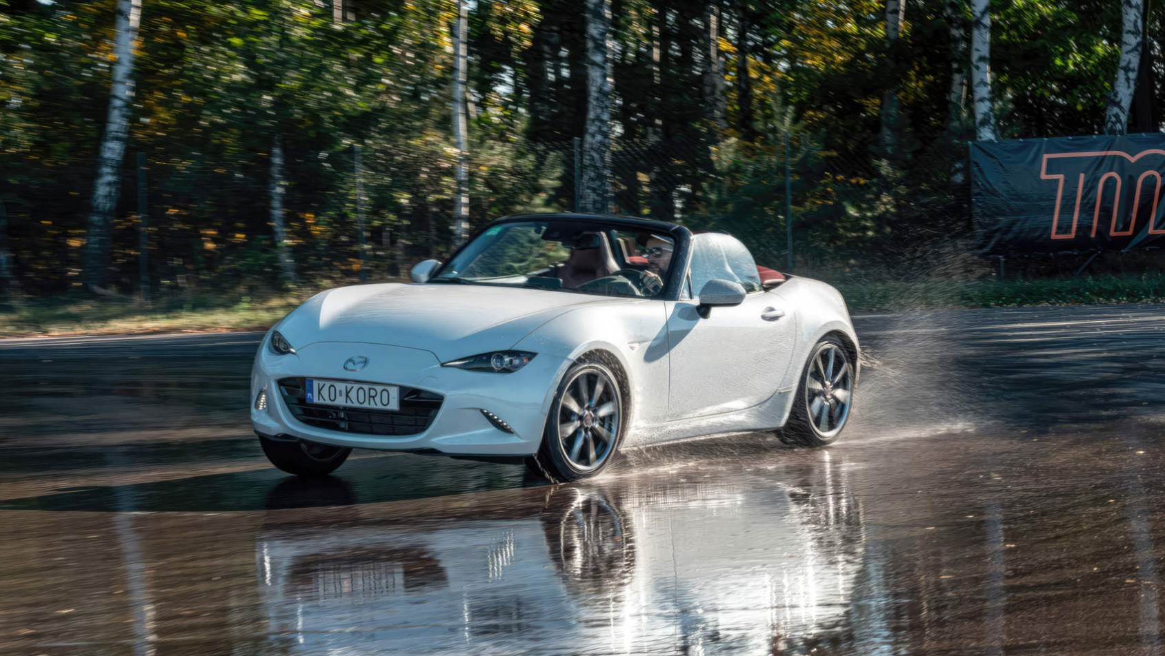 Biała Mazda MX-5 testuje przyczepność na mokrym