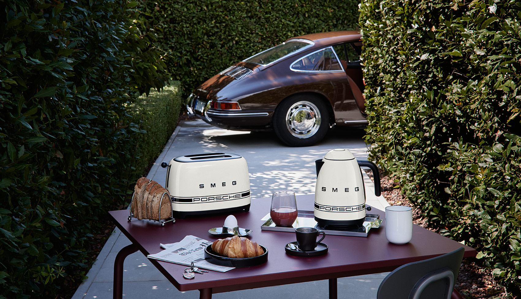 SMEG x Porsche – klasyka w towarzystwie legendy Toster i czajnik Porsche x SMEG Carrara White na stole obok klasycznego Porsche 911