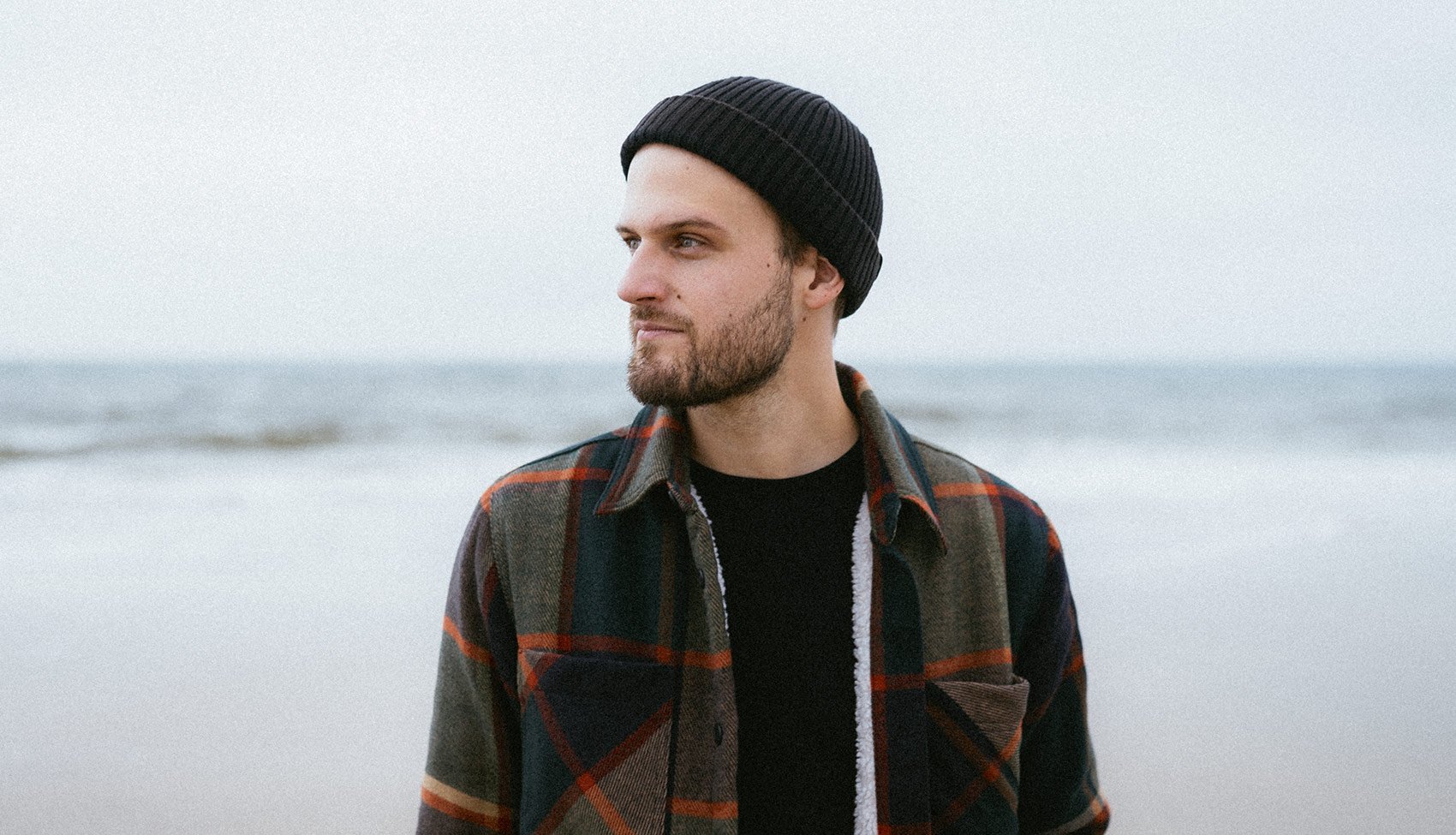 Portret Bartka Kołaczkowskiego, fotografa i podróżnika, uchwyconego w naturalnym świetle podczas pracy w terenie – spokojny moment skupienia przed kolejną wyprawą.