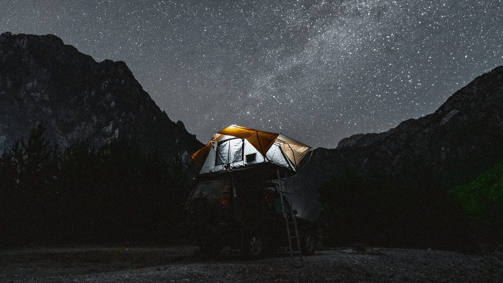 Namiot dachowy na Land Roverze podczas noclegu w korycie rzeki Lumi i Shales w Albanii, idealny kadr do astrofotografii