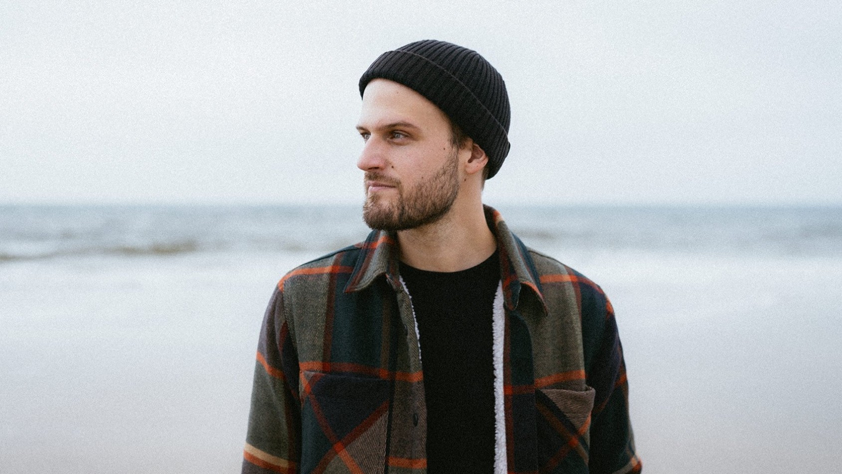 Portret Bartka Kołaczkowskiego, fotografa i podróżnika, uchwyconego w naturalnym świetle podczas pracy w terenie – spokojny moment skupienia przed kolejną wyprawą.