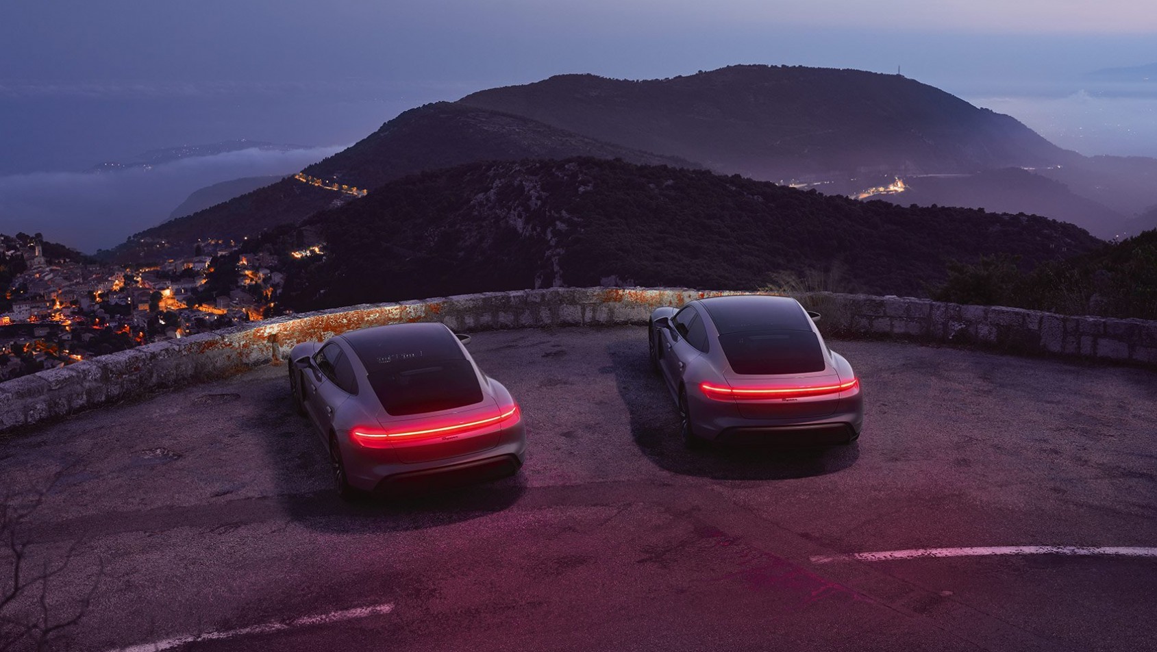 Dwa Porsche Taycan sfotografowane o zmierzchu w górskim pejzażu – artystyczna interpretacja elektrycznej motoryzacji w obiektywie Tomka Mąkolskiego.