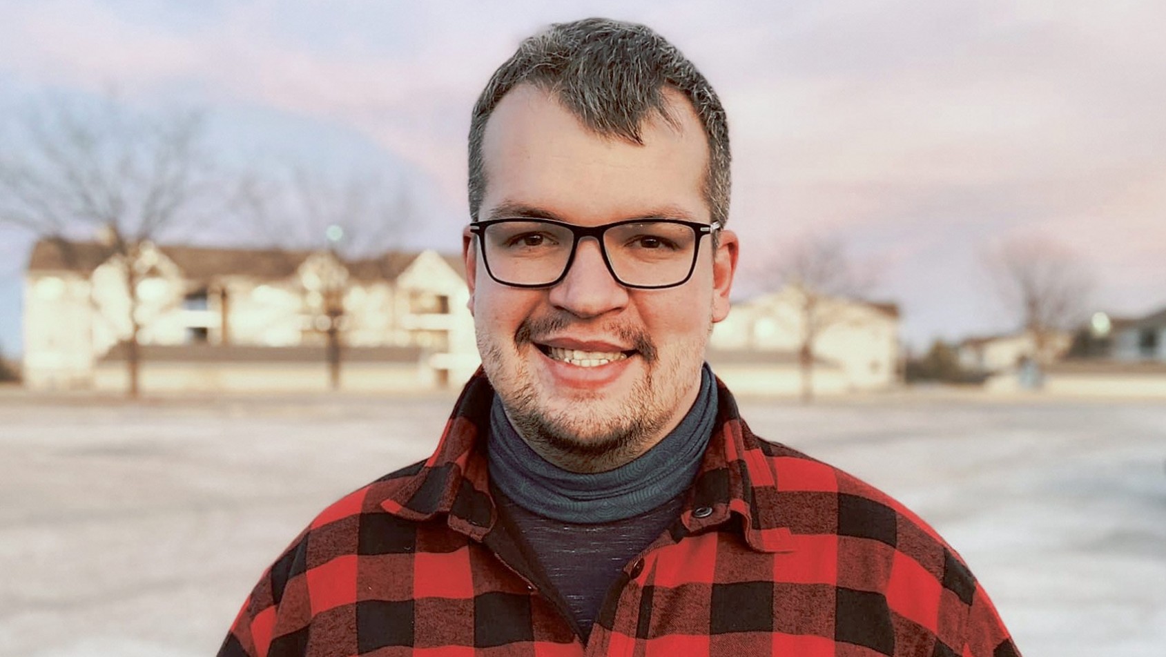 Paweł Sudoł – fotograf i operator drona w czerwonej koszuli, uśmiechnięty, w plenerze