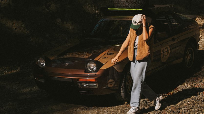 Kobieta przy klasycznym Porsche 944 Dakarista w rajdowej stylistyce vintage