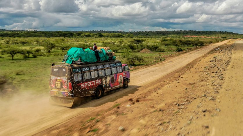 Ujęcie z drona przedstawiające barwny autobus jadący po pustynnej drodze w Afryce