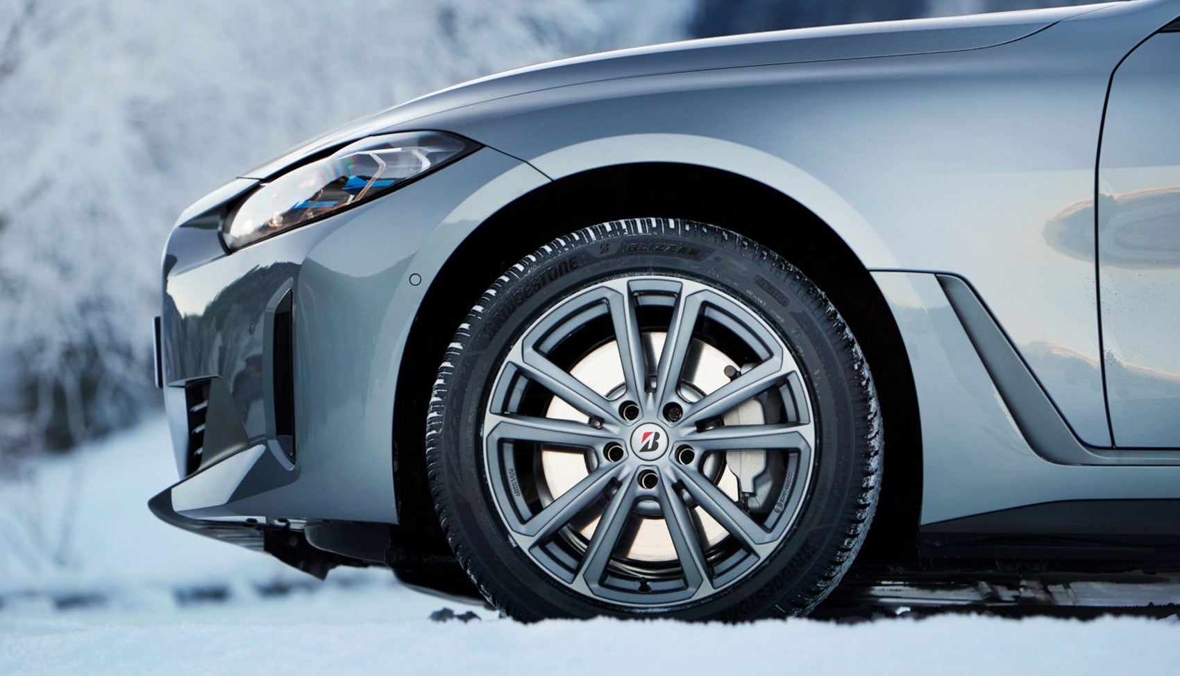 Samochód wyposażony w opony Bridgestone podczas jazdy po śniegu.