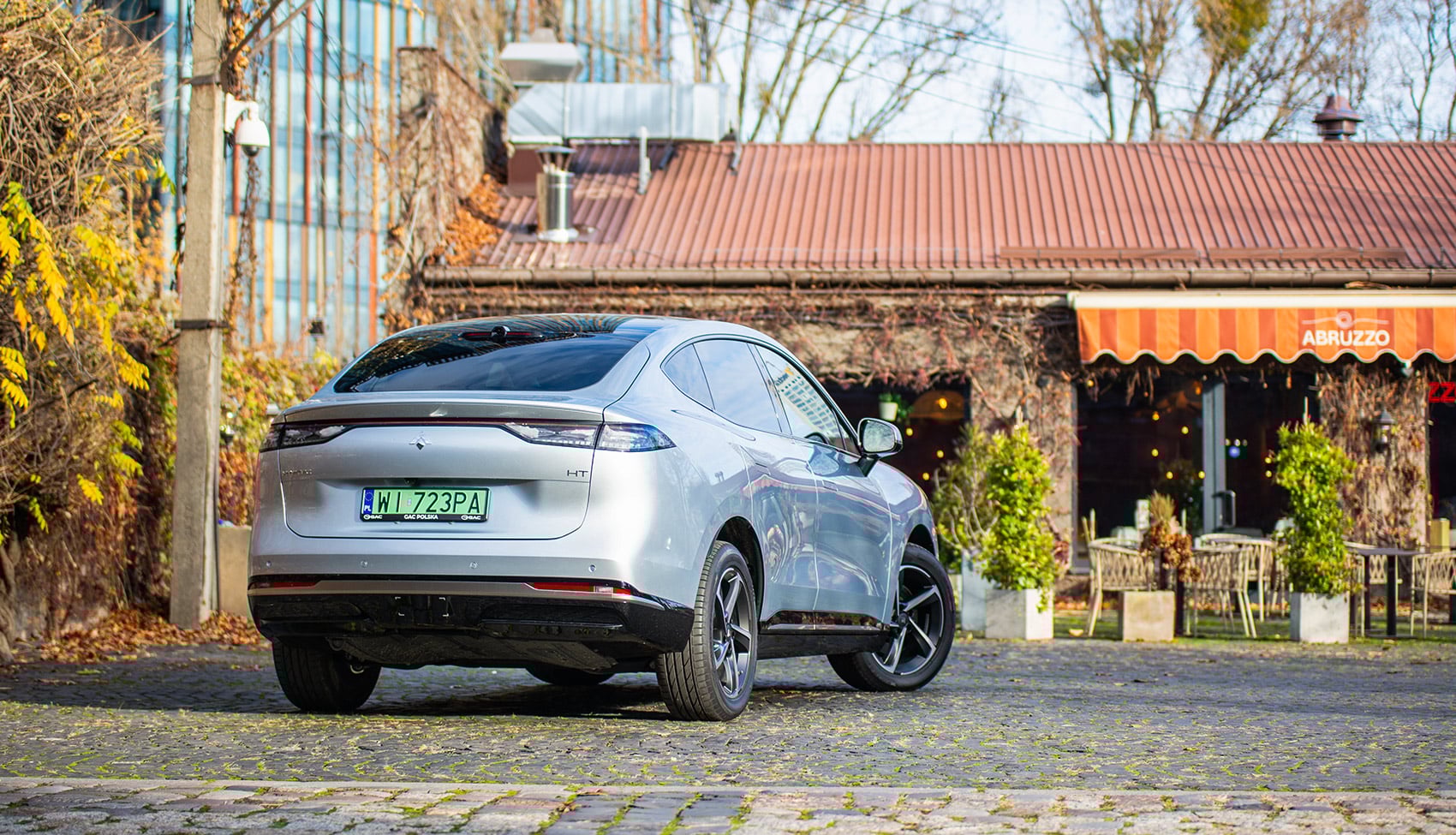 Tylny widok GAC Hyptec HT zaparkowanego na&nbsp;brukowanej ulicy przy restauracji