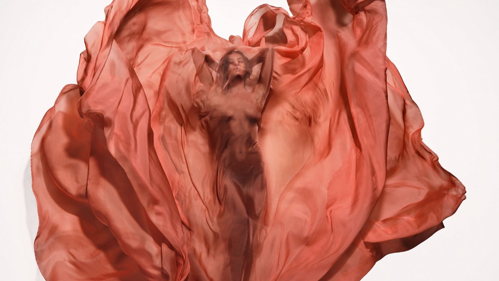 Irina Shayk otulona falującą czerwoną tkaniną w dynamicznej interpretacji żywiołu ognia