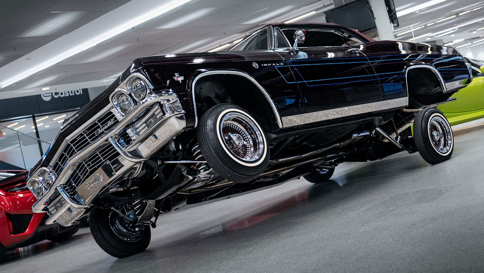 Czarny Chevrolet Impala Lowrider unoszący się na hydraulice, prezentowany w hali Wystawy Castrol Ikony Motoryzacji