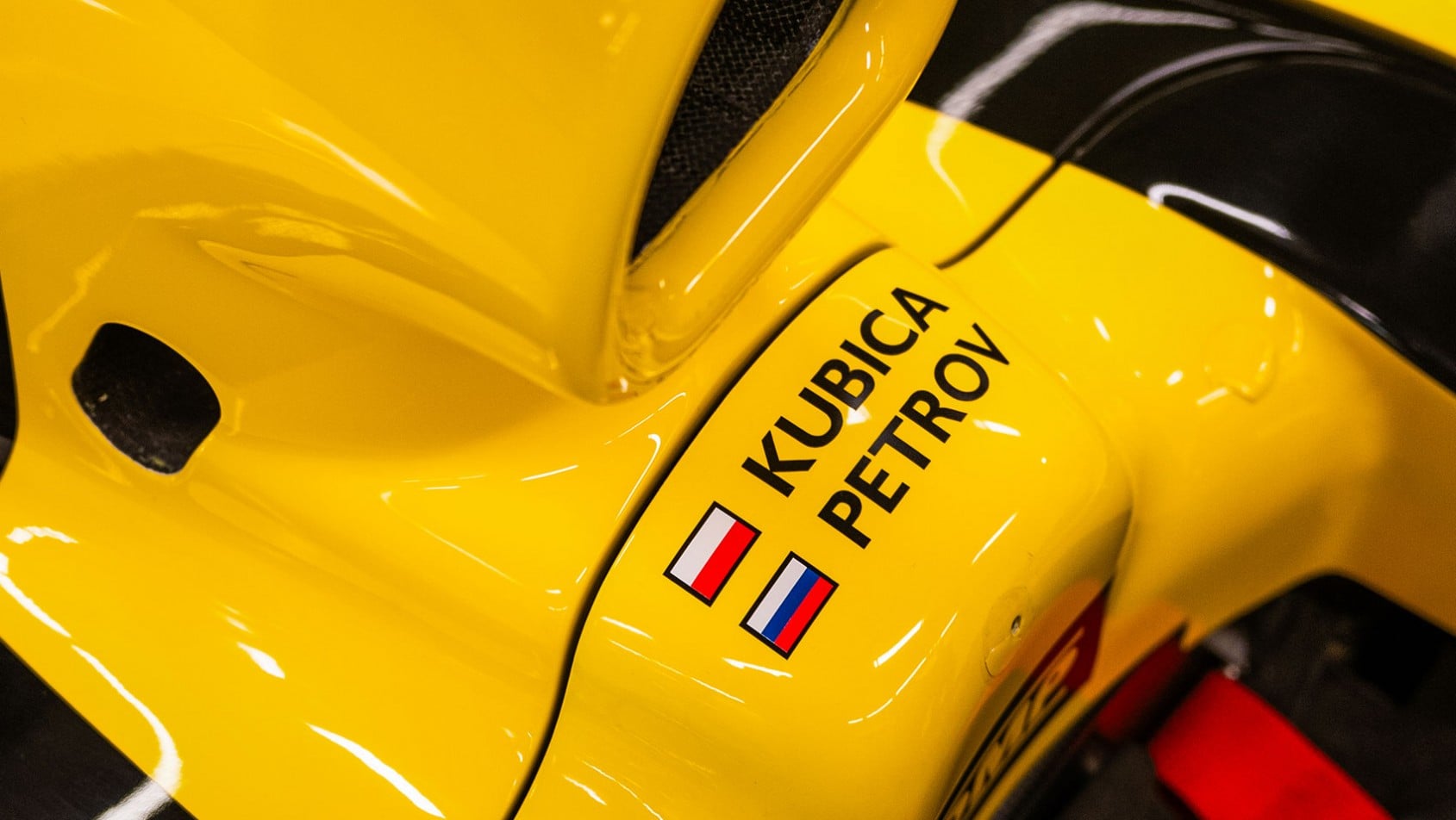 Zbliżenie na żółto-czarne nadwozie bolidu Renault F1 z oznaczeniami Kubica i Petrov oraz flagami Polski i Rosji