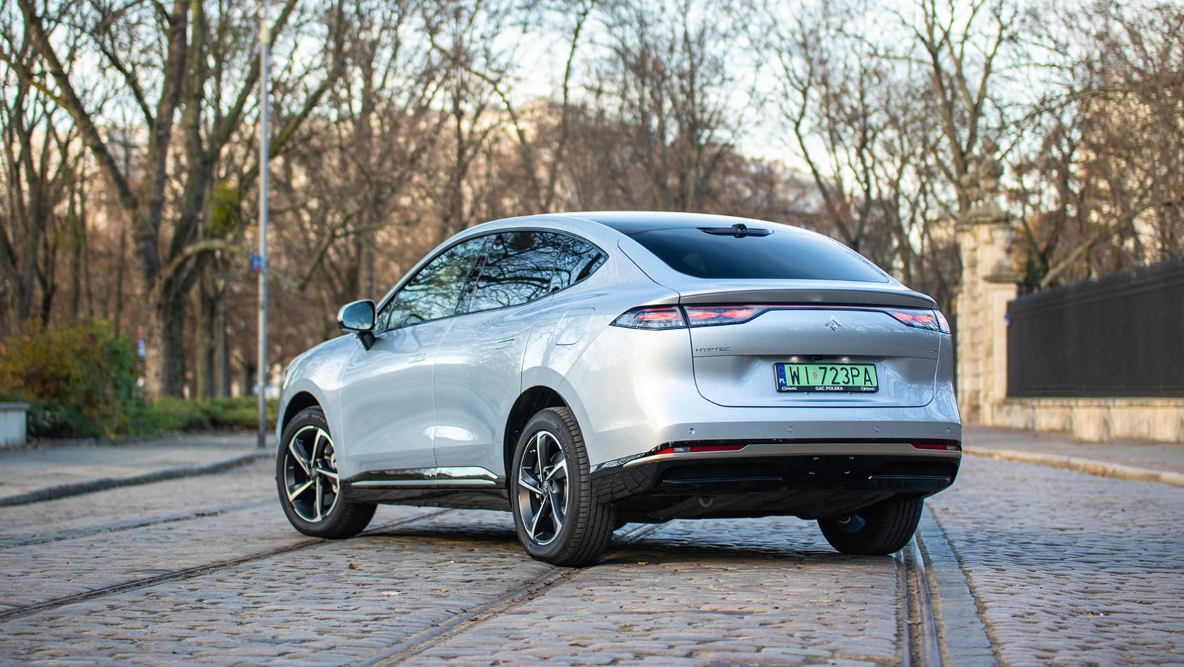 Tył i bok GAC Hyptec HT na brukowanej ulicy, z widoczną linią świateł i felgami