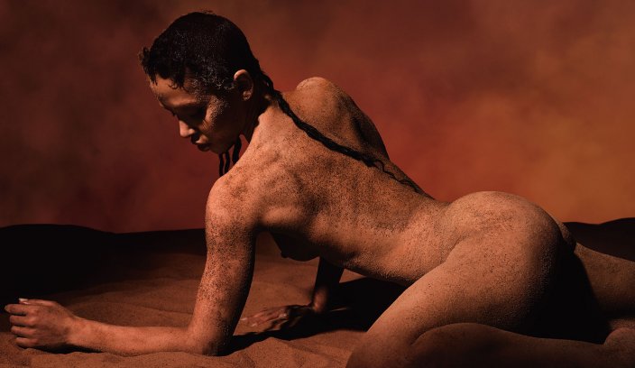 FKA twigs pokryta ziemią i piaskiem, w pozie odwołującej się do surowej, pierwotnej natury żywiołu ziemi
