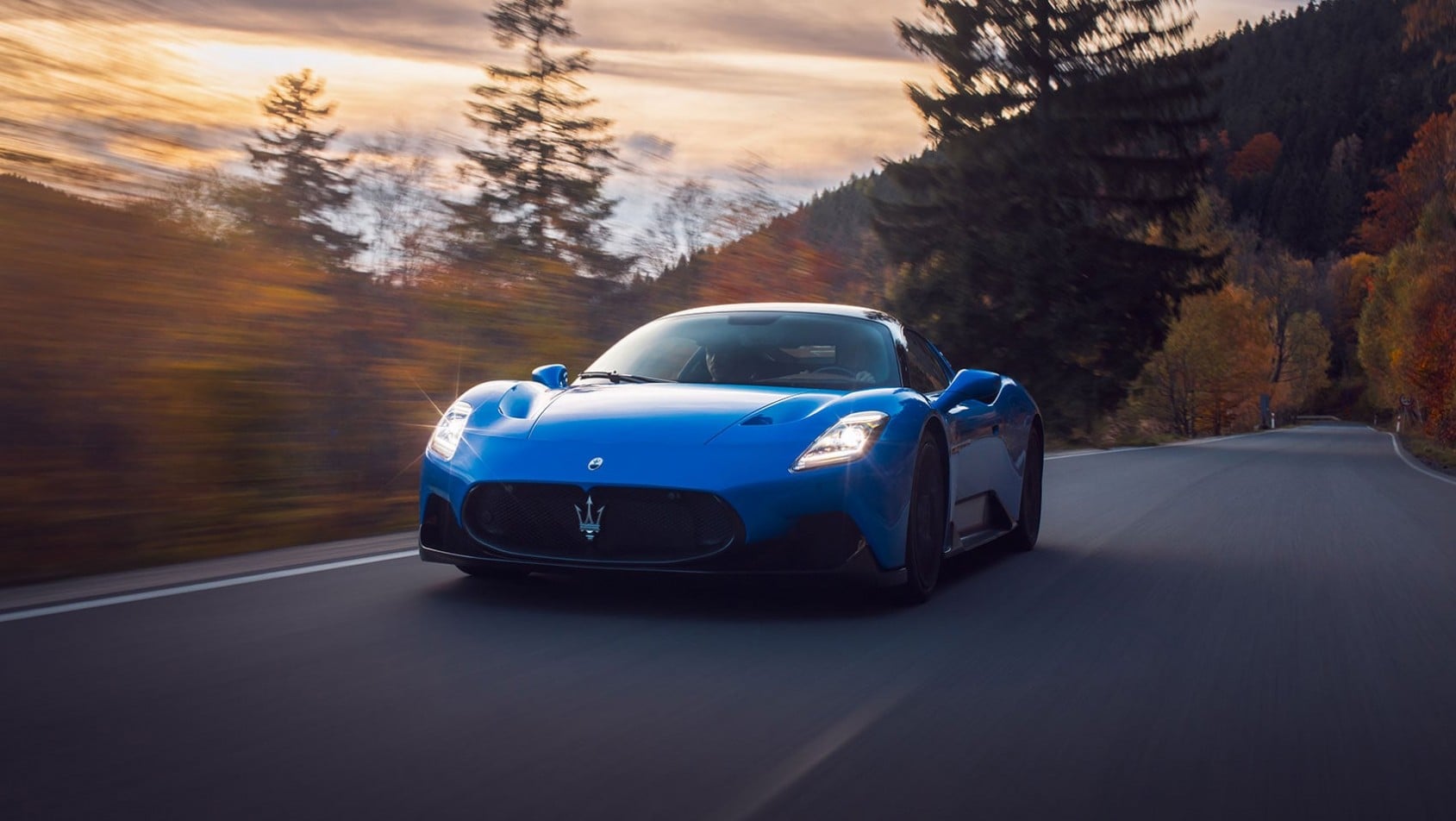 Sportowe Maserati jadące krętą drogą w jesiennym lesie