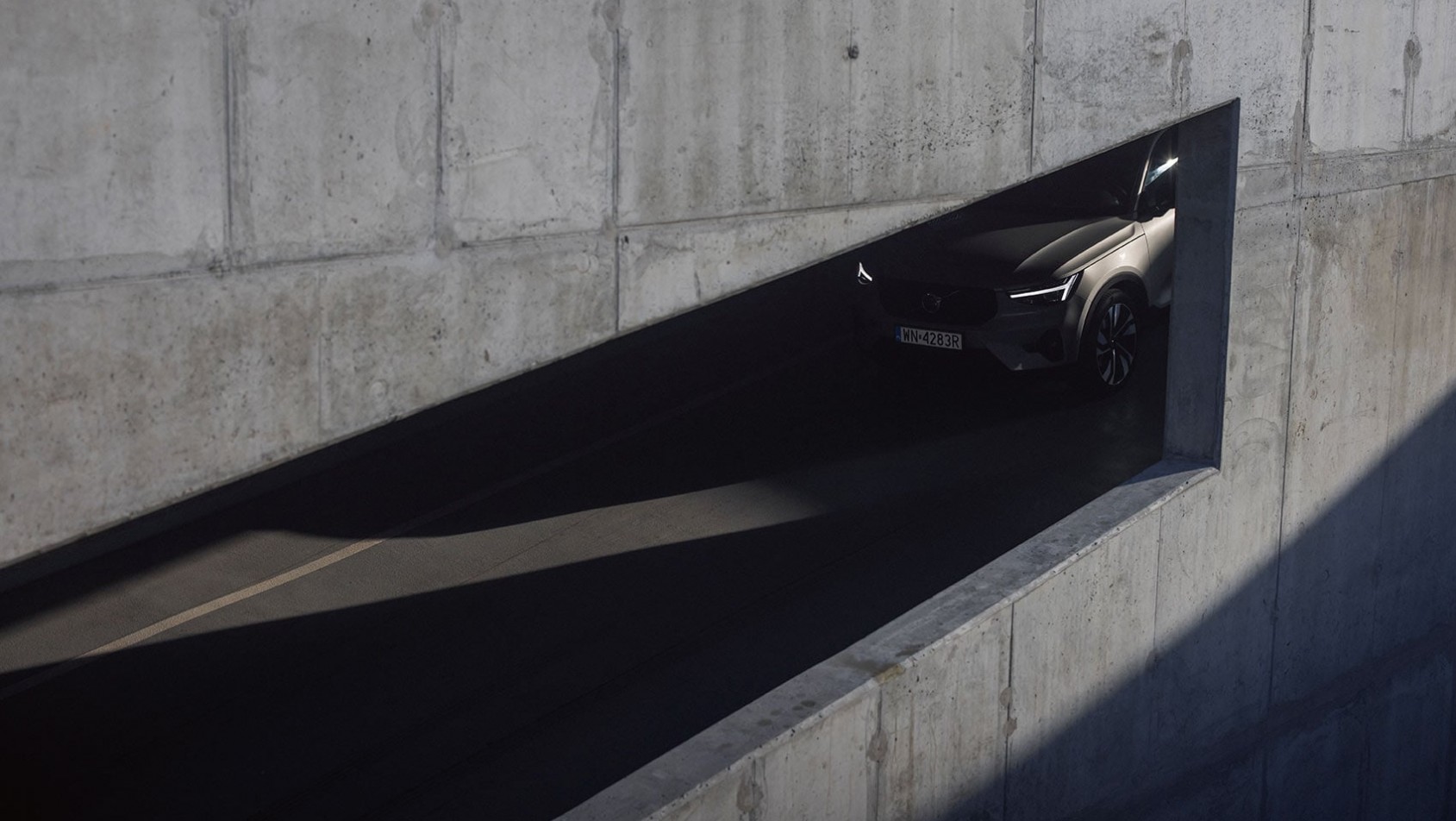 Samochód wyłaniający się z betonowego tunelu w minimalistycznej architekturze