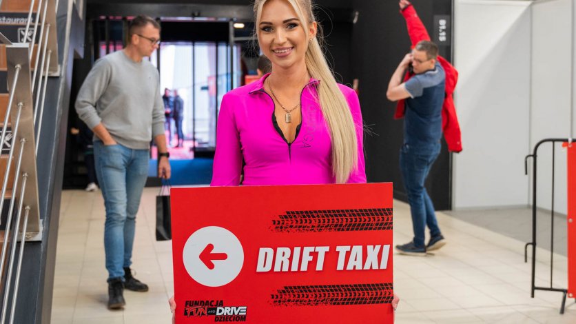 Hostessa z tablicą Drift Taxi kieruje uczestników na przejazdy driftingowe podczas wydarzenia