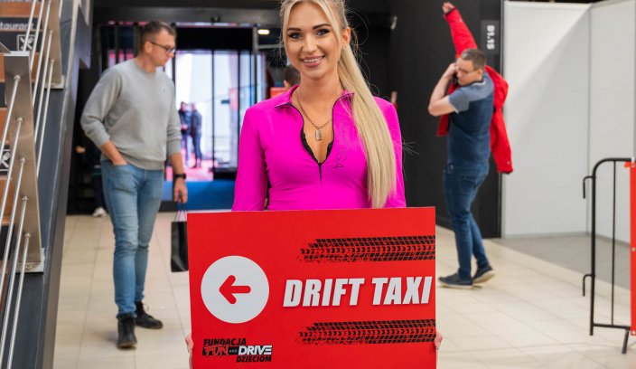 Hostessa z tablicą Drift Taxi kieruje uczestników na przejazdy driftingowe podczas wydarzenia