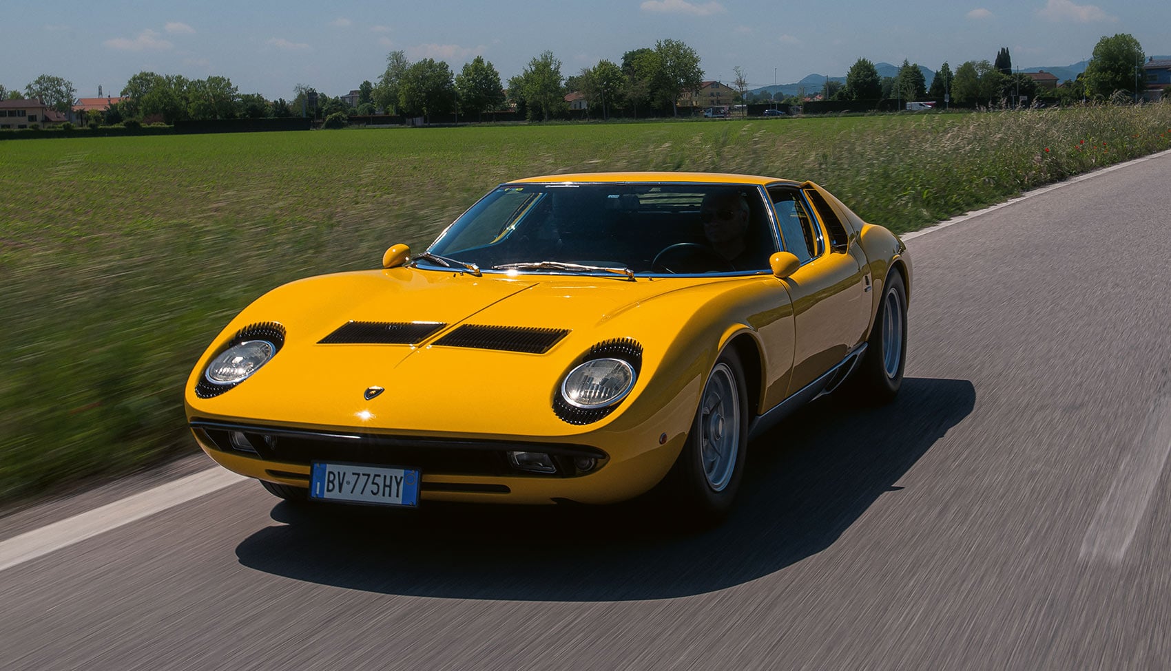 Żółte Lamborghini Miura P400 S jadące autostradą widziane z&nbsp;przodu