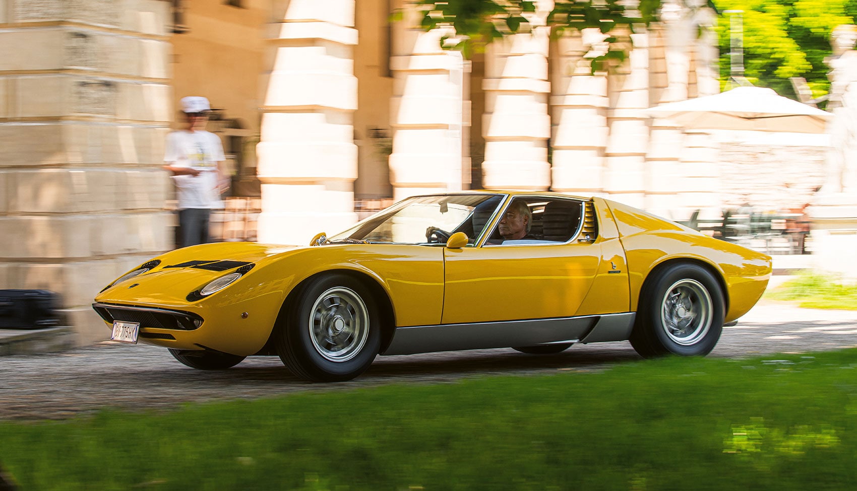 Żółte Lamborghini Miura P400 S jadące obok zabytkowego pałacu
