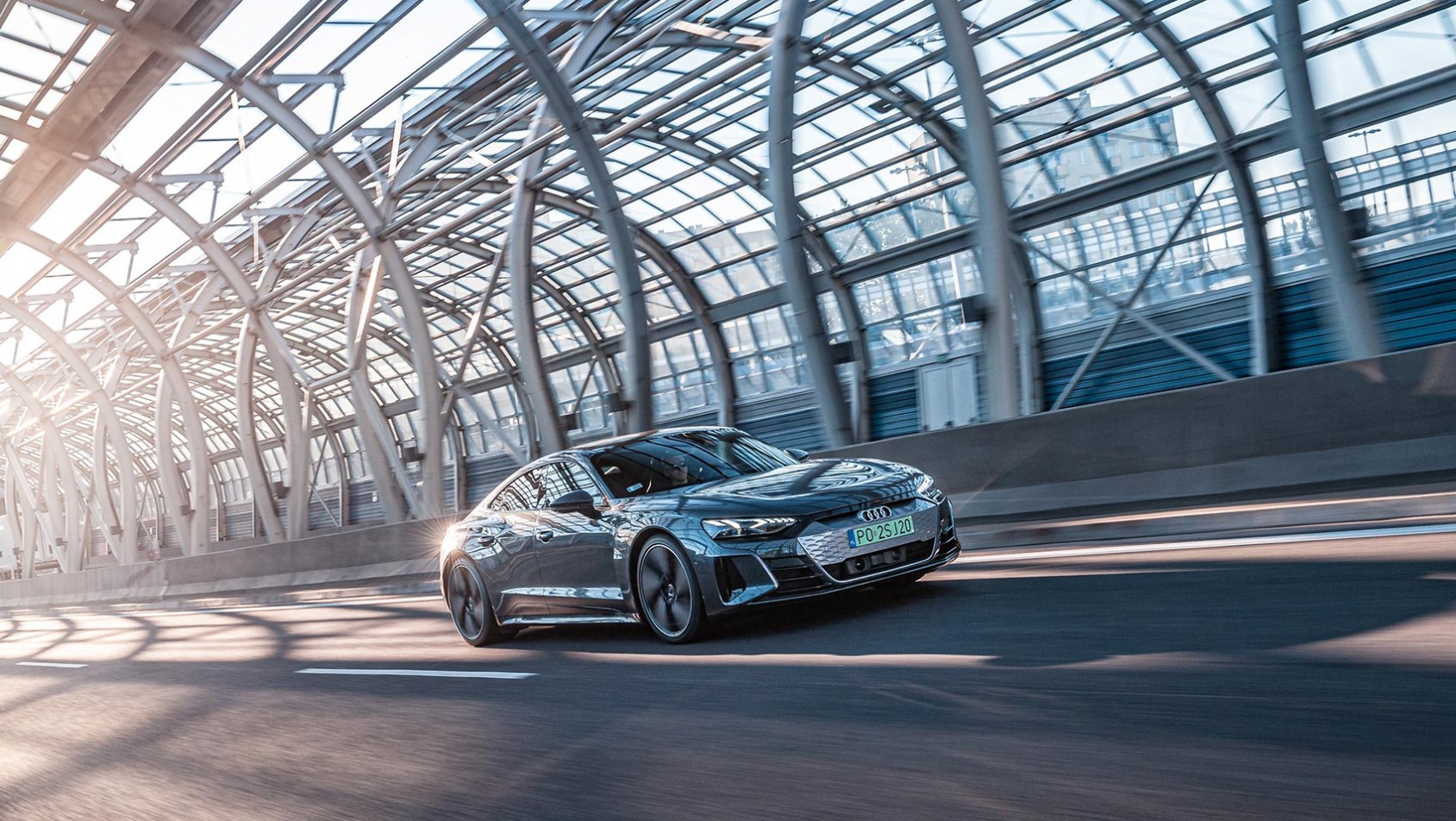 Audi e-tron GT sfotografowane podczas jazdy w nowoczesnej architekturze