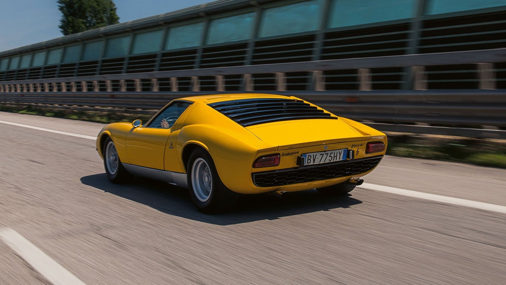 Żółte Lamborghini Miura P400 S jadące drogą