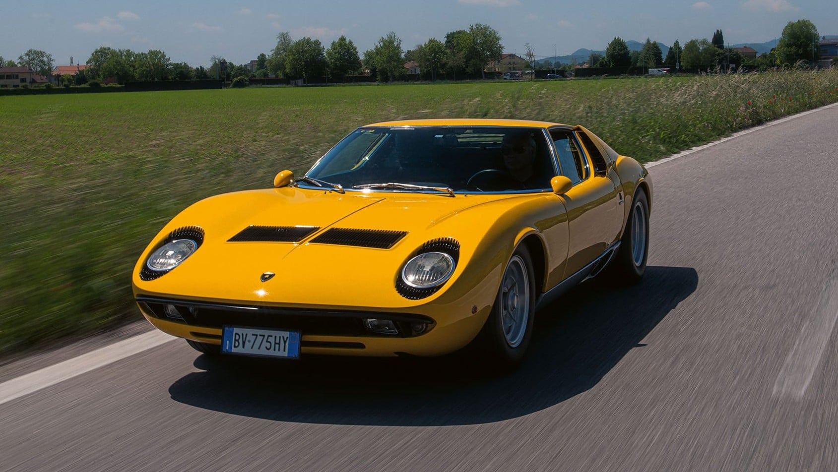 Żółte Lamborghini Miura P400 S jadące autostradą widziane z przodu